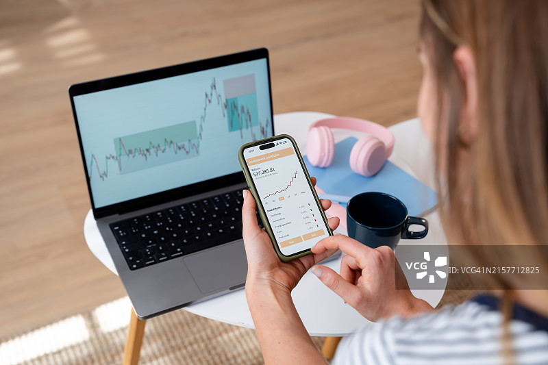 女商人用智能手机和显示图表的笔记本电脑分析股票市场数据图片素材