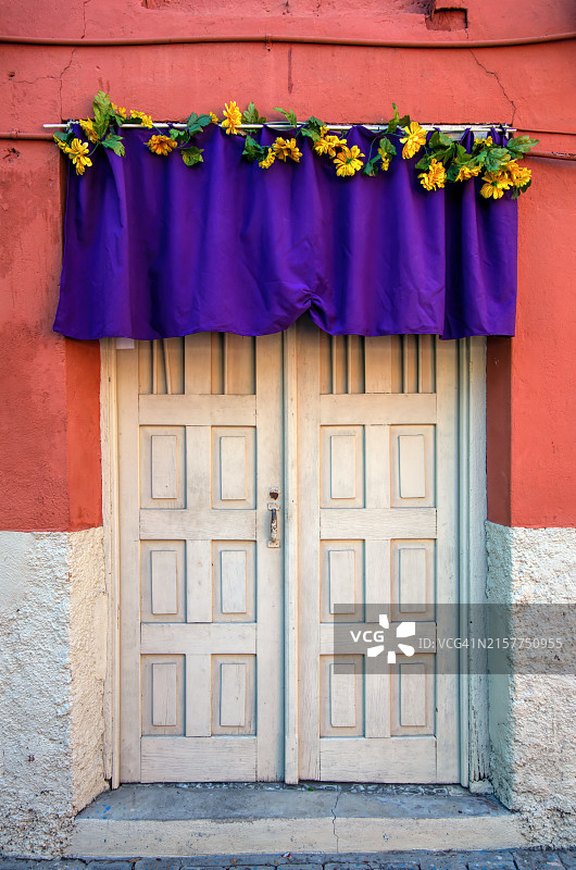 圣周期间殖民风格房屋前门悬挂的紫色帷幔和织物花卉装饰图片素材