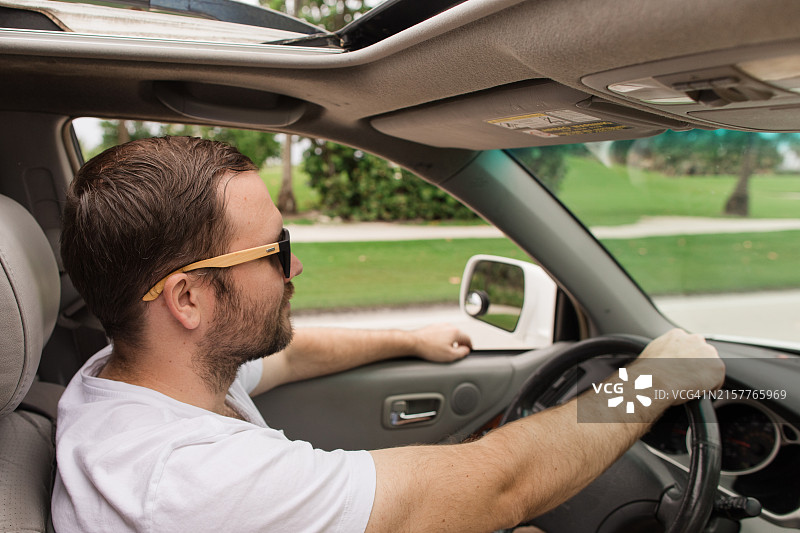 一位33岁的美国男子戴着太阳镜，在佛罗里达棕榈滩海边开着敞篷车兜风图片素材