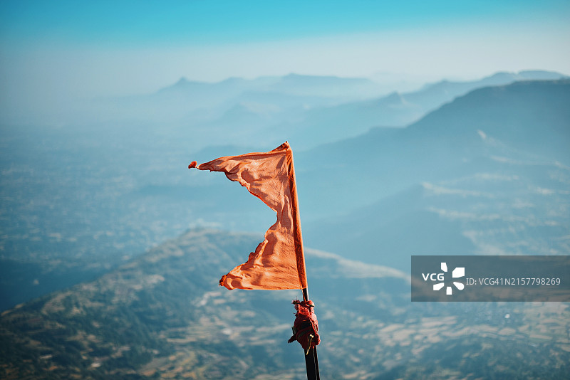 山顶上迎风飘扬的橙色旗帜图片素材