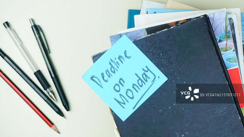 白色桌面上堆叠的书本和文具上的截止日期提示图片素材