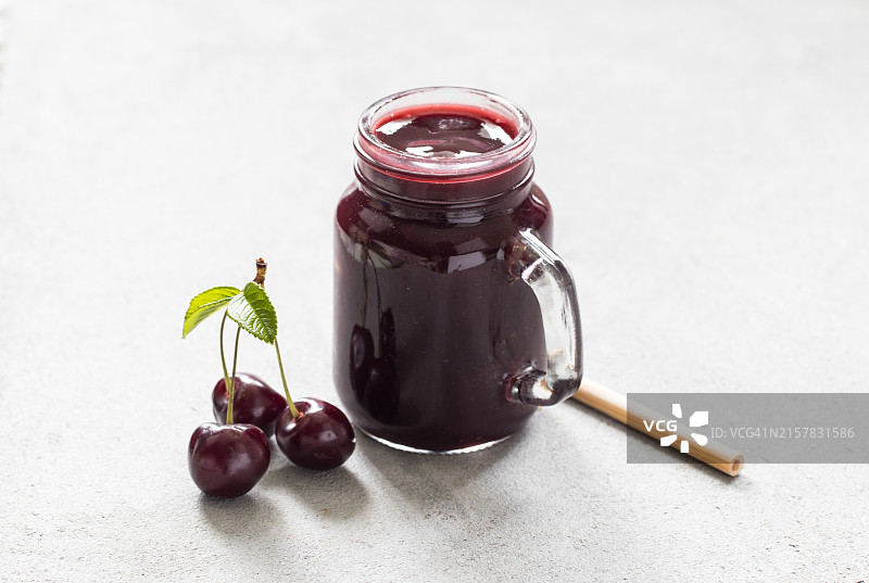 玻璃罐装樱桃冰沙，配竹吸管，浅灰色背景，特写图片素材