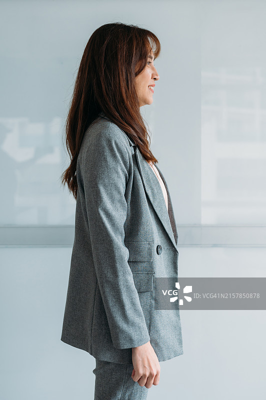 身穿西装的中国女商人站在纯色背景前图片素材