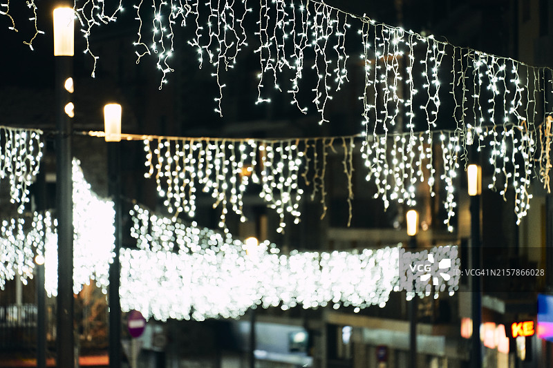 房屋外街道上悬挂的圣诞彩灯侧面图片素材