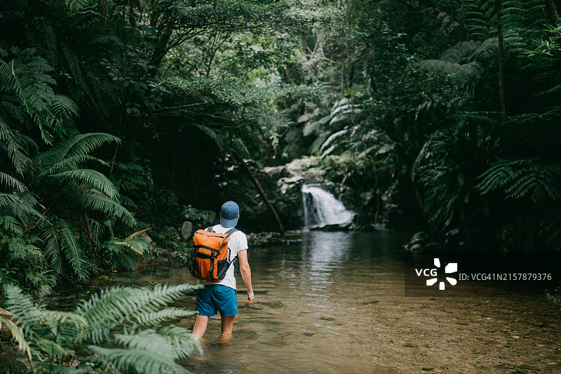 徒步穿越丛林河流的男人图片素材