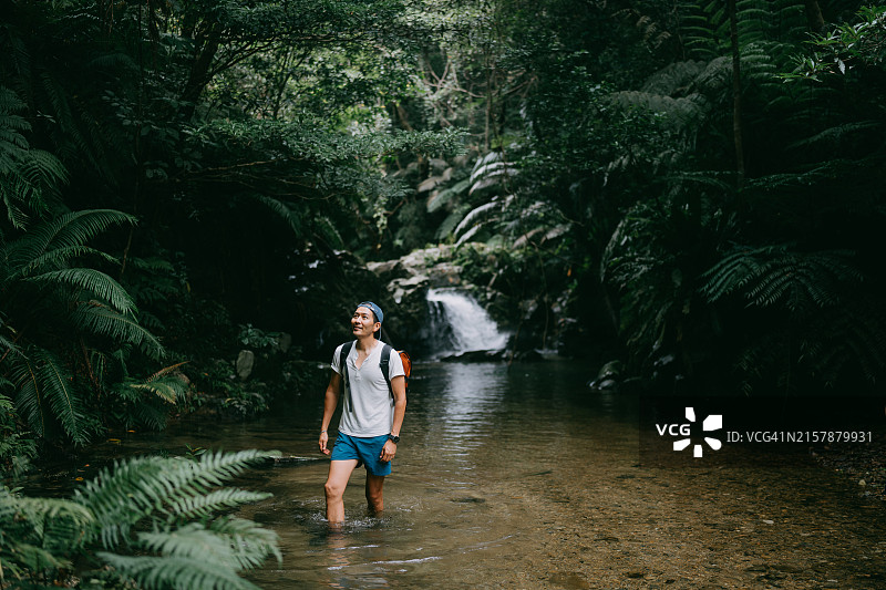 徒步穿越丛林河流的男人图片素材