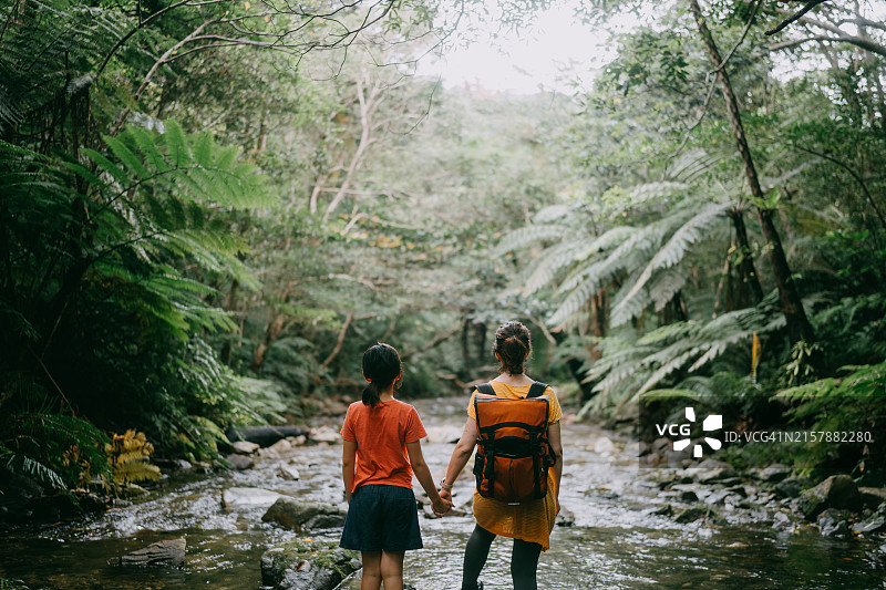 母女在热带雨林中的河流中徒步旅行图片素材