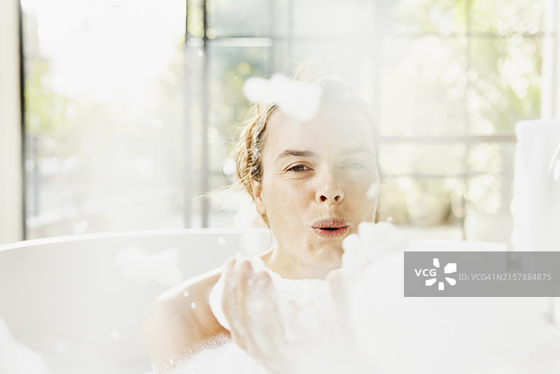 酒店套房里吹泡泡的微笑女性图片素材