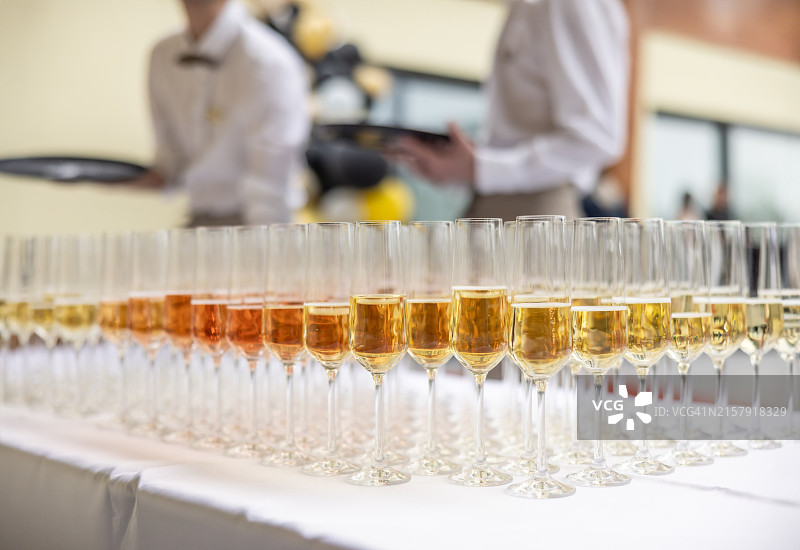 在婚礼或公司活动中，酒保拿着一杯香槟或普罗塞克葡萄酒。服务员为客人提供迎宾饮品图片素材
