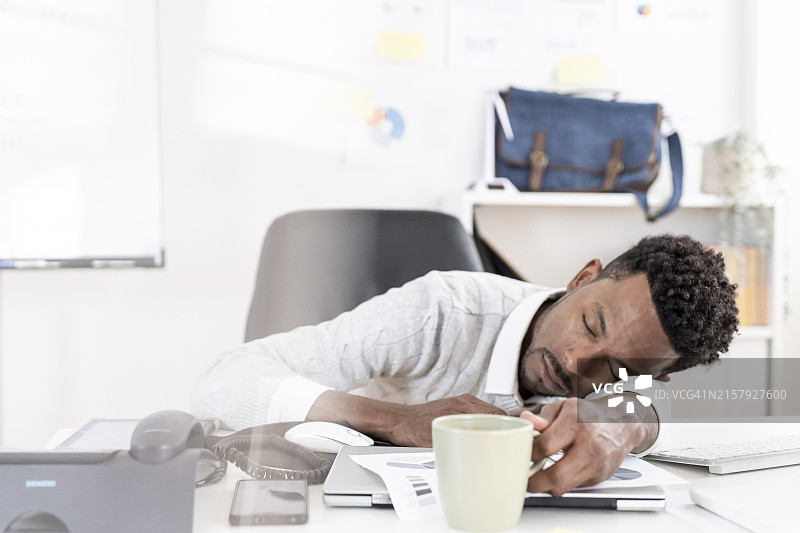 男子在办公室里头靠在桌子上睡觉图片素材
