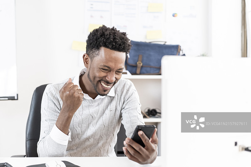 在办公室使用手机庆祝的商人图片素材