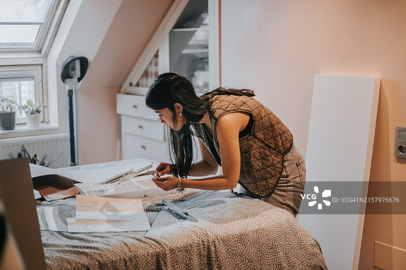 年轻女人参照说明书组装新抽屉桌。家具组装。图片素材