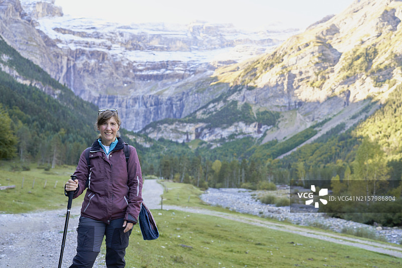 穿着运动服，手持登山杖，在Gavarnie土路上微笑看向镜头的女人图片素材