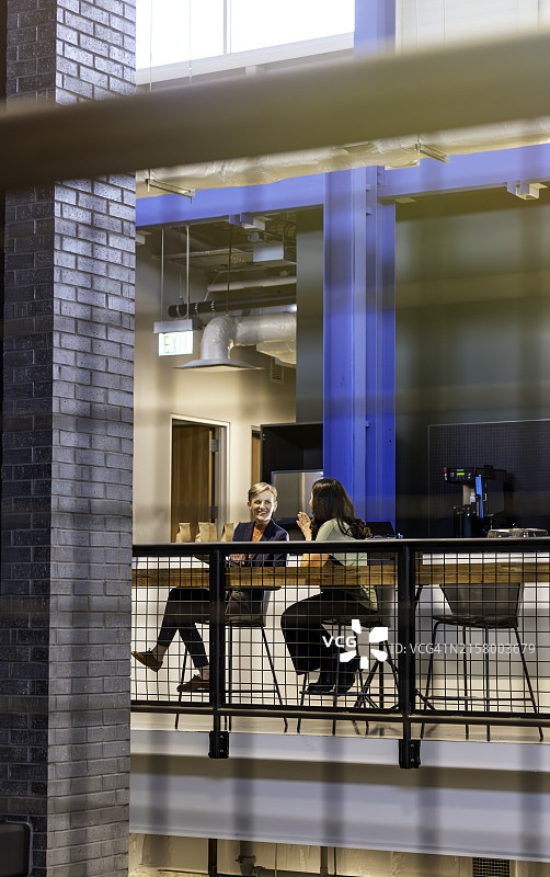 两位职业女性在咖啡馆里笑着聊天休息图片素材