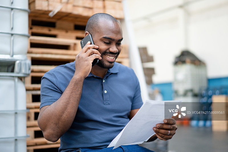 仓库工人查看文件时正在打电话图片素材