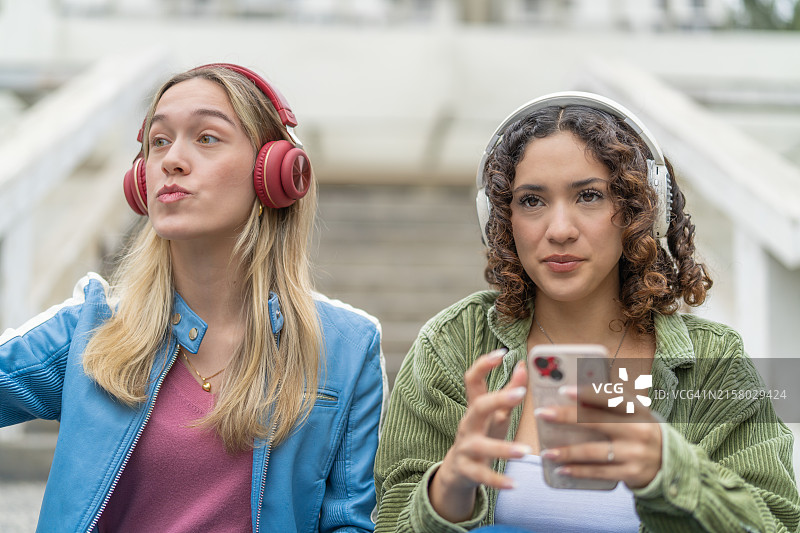 朋友们坐在楼梯上听音乐，使用手机图片素材