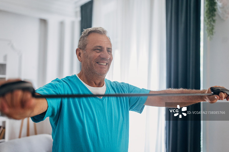 在家中使用阻力带的年长的男人图片素材