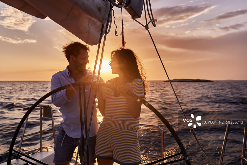 夕阳下，幸福情侣在游艇上举杯庆祝。图片素材
