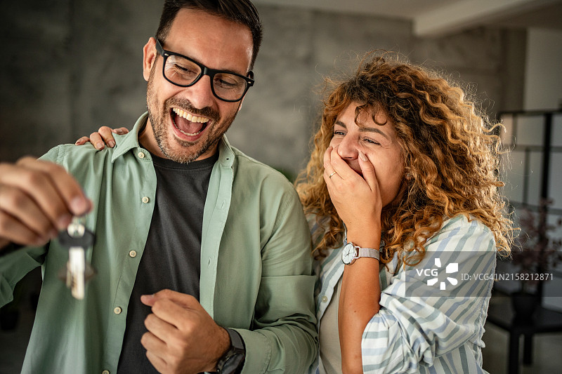 新的开始：一对快乐的夫妇拿着他们新家的钥匙图片素材