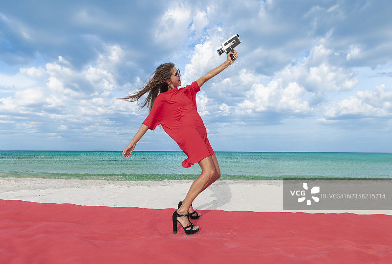 女人在海滩上用8毫米复古电影相机自拍图片素材