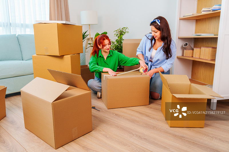 在新家搬运箱子的年轻女人，情侣在新家打开箱子图片素材