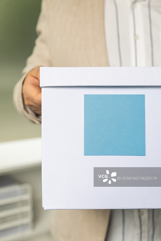 男人拿着带有蓝色纸条的盒子。有文案和广告的空白区域图片素材