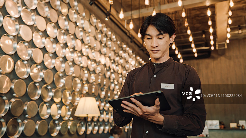 酒店员工在具有现代照明的时尚大堂中使用平板电脑，氛围专业而温馨图片素材