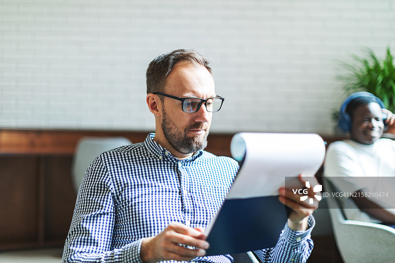 中年金融顾问仔细阅读新协议图片素材