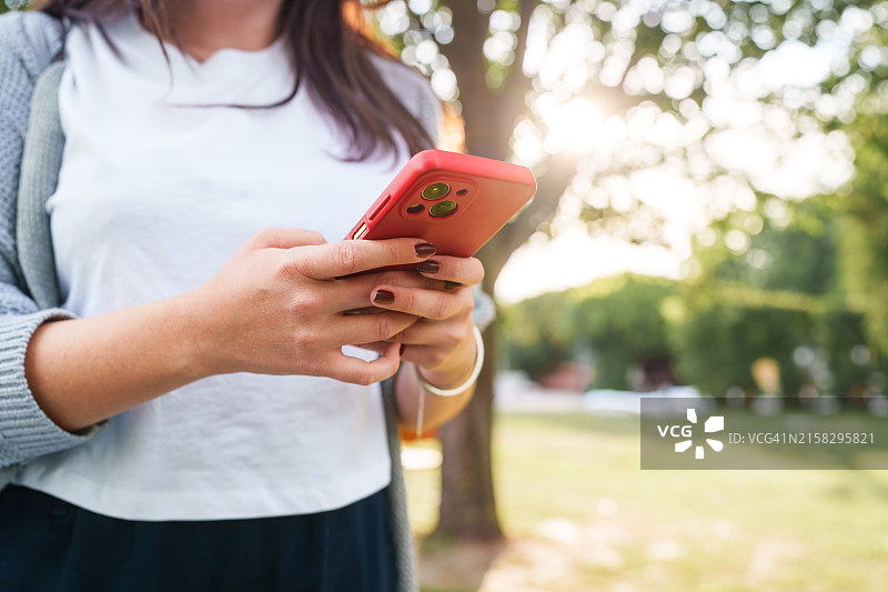 大学生在公园使用手机的日常图片素材