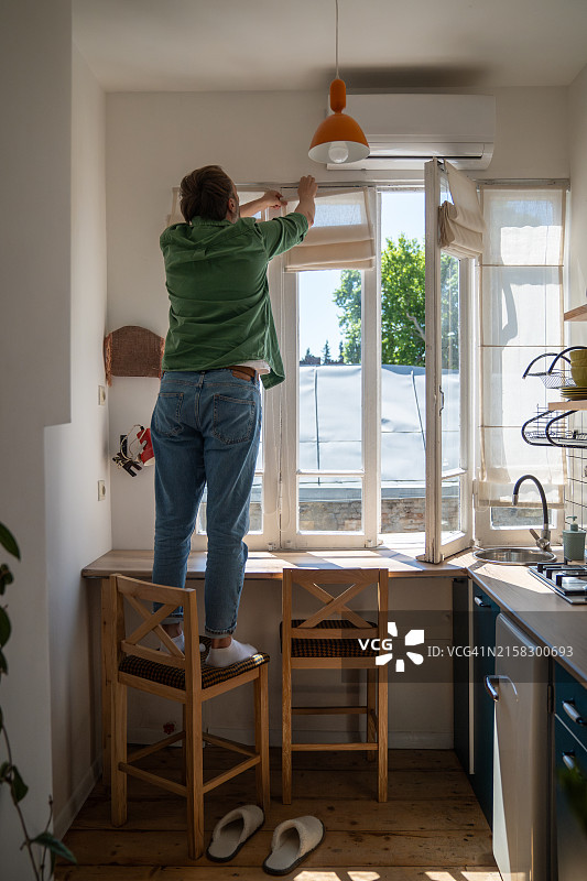 熟练男子在厨房安装罗马帘图片素材
