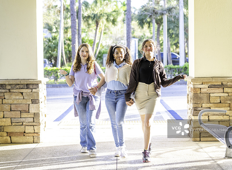 三个快乐微笑的不同肤色的可爱初中少女在户外随意的朋友合影中表现得很傻气图片素材