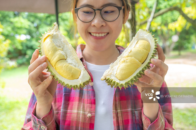 年轻亚洲女性手拿打开的榴莲食用图片素材