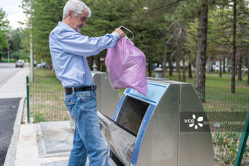 将食物垃圾扔进金属垃圾回收容器图片素材