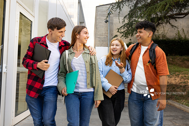 快乐的大学生们在大学建筑外一起散步欢笑图片素材