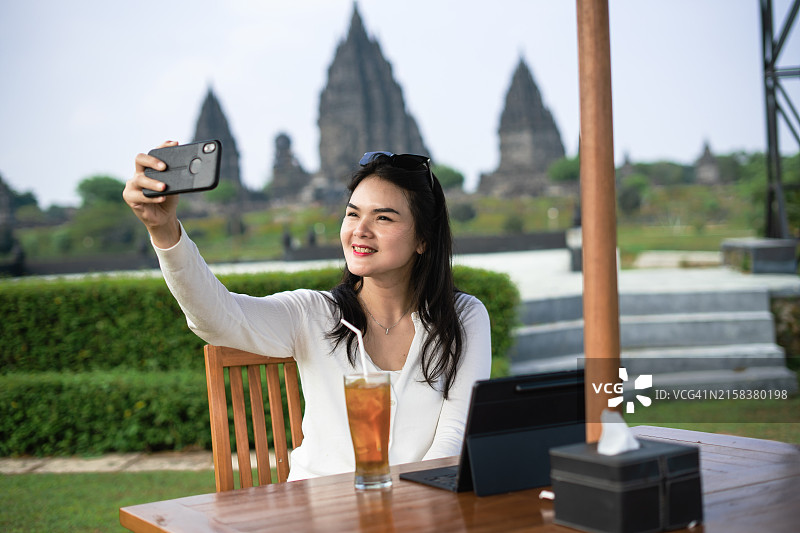 在餐厅自拍的亚洲女性，背景是普兰巴南寺庙图片素材