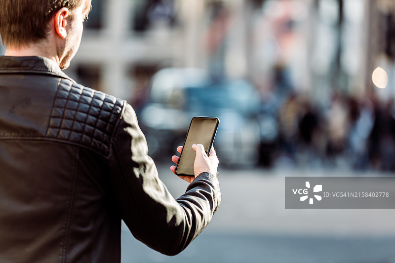 在街上使用智能手机的男人（后视图）图片素材