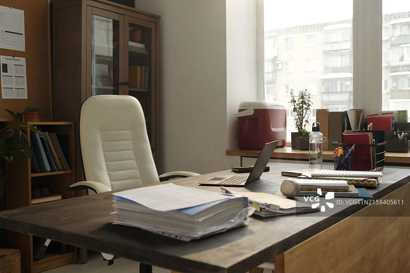 大学办公室书桌旁的白色椅子与办公用品文件图片素材