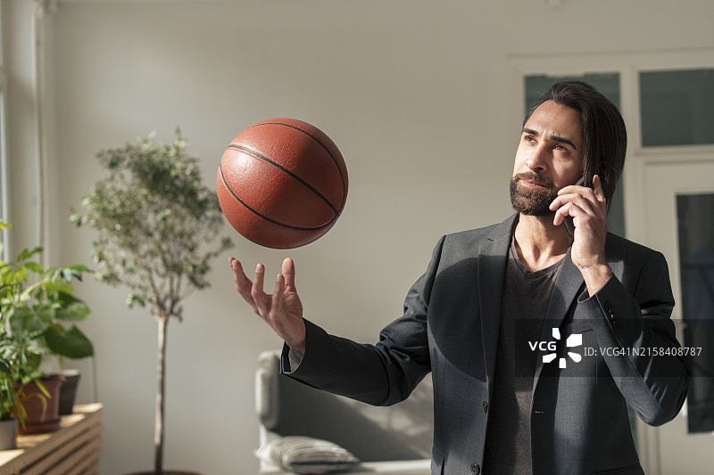 商务男士在办公室用手机交流和投掷篮球图片素材