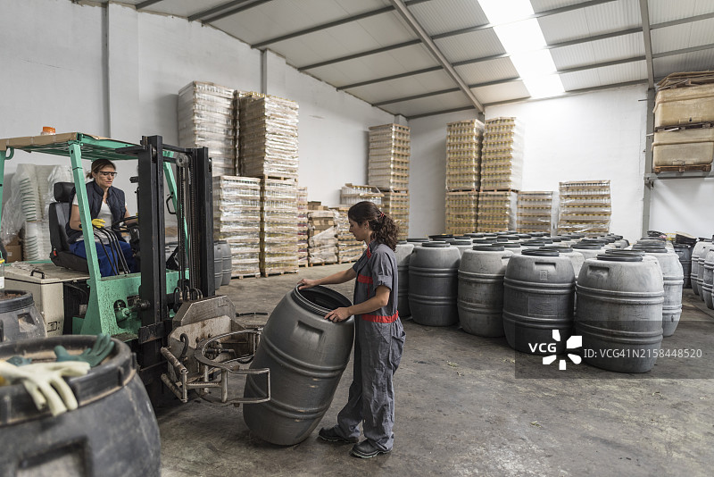 妇女在橄榄工厂工作，驾驶夹钳式叉车图片素材