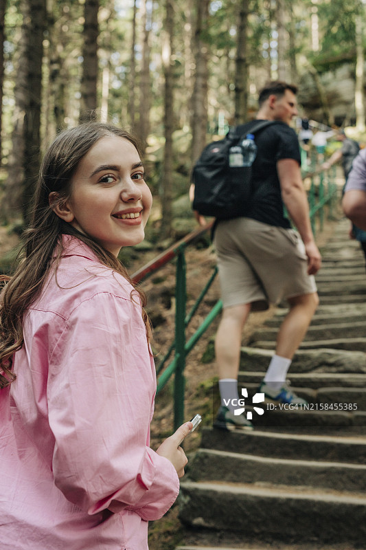 快乐的年轻女人站在森林的楼梯上图片素材