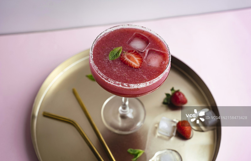 金色托盘中盛有草莓玛格丽特鸡尾酒，配以薄荷和冰块。夏季饮品。图片素材