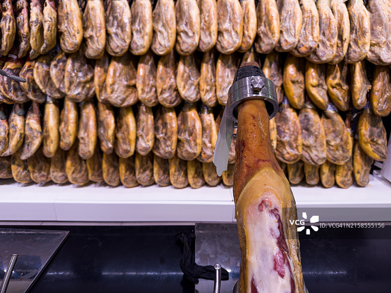 待切的腌制火腿与悬挂的火腿图片素材