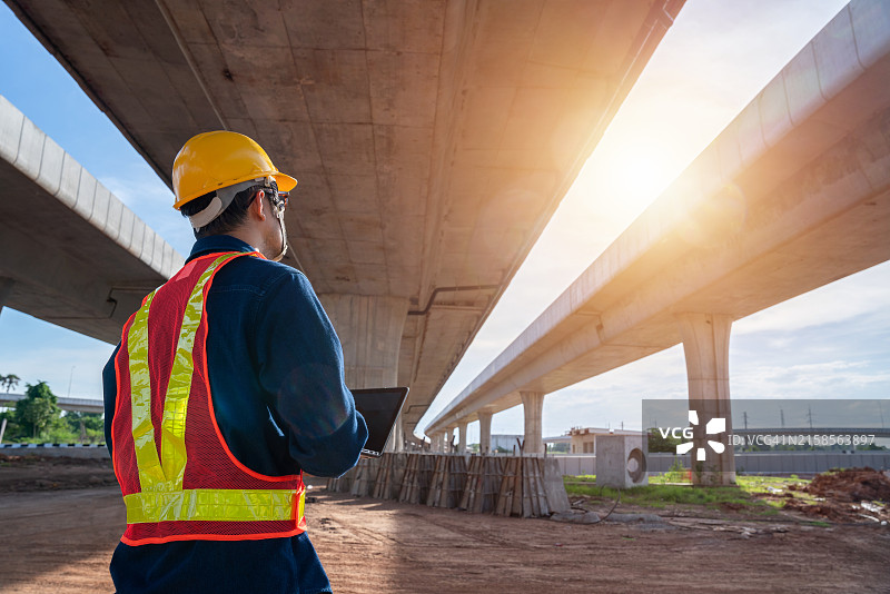 亚洲年轻的土木工程师在道路施工现场检查道路结构工程。监督新道路建设。在高速公路建设中的土木工程师。图片素材