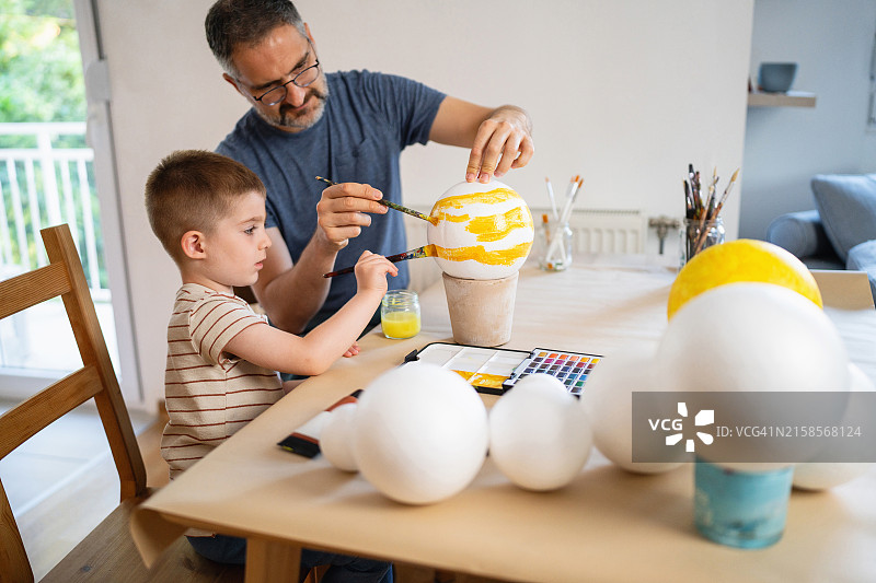 父子在家绘制太阳系模型图片素材