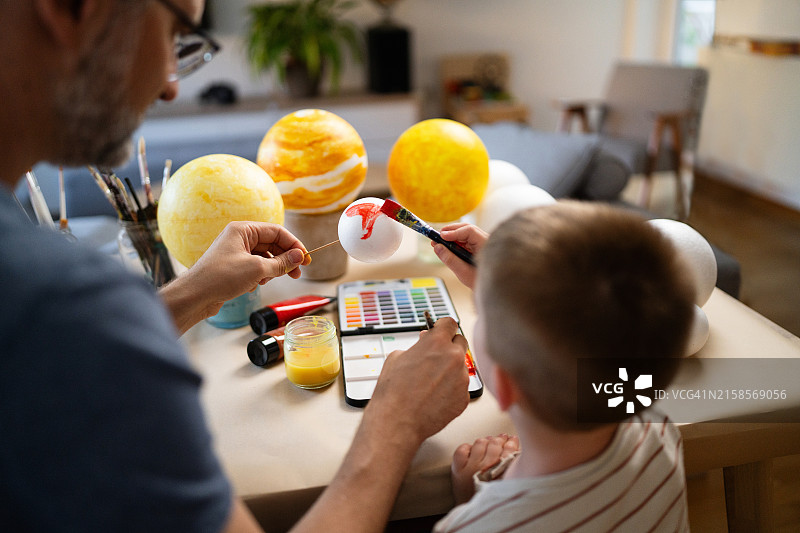 父子在家绘制太阳系模型图片素材