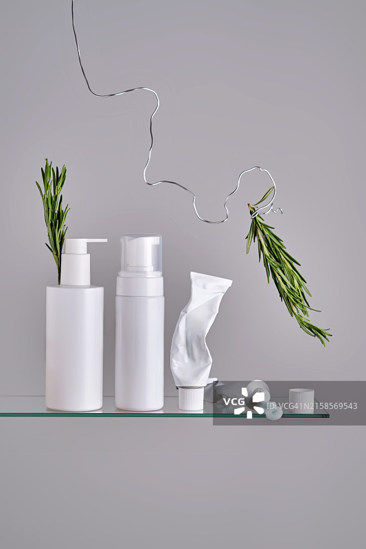 浴室玻璃架子上带有迷迭香的各种面部和身体护理产品图片素材