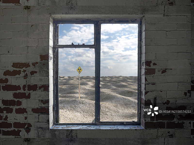 透过废墟建筑的窗户看到的带有辐射警告标志的沙漠图片素材