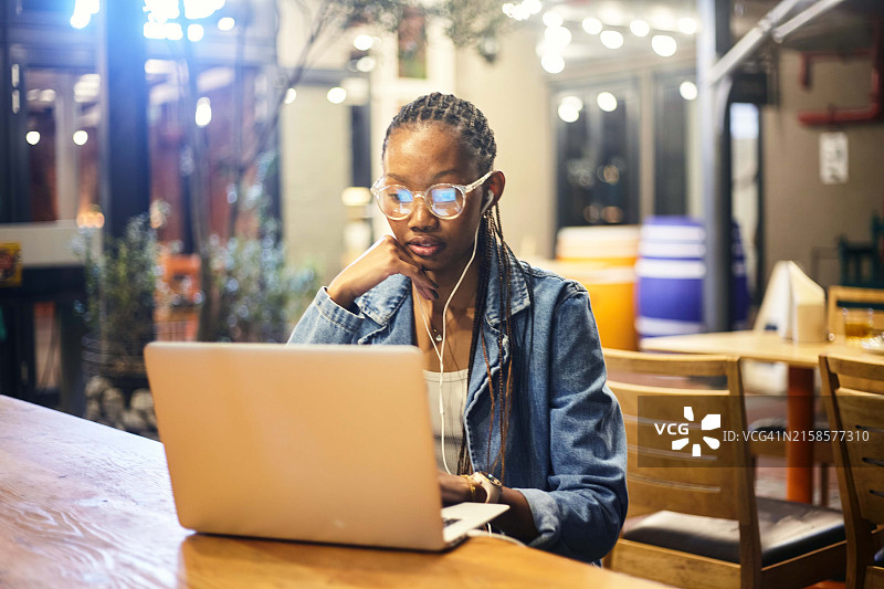 咖啡馆纪事：沉浸在笔记本电脑和耳机中的女人图片素材
