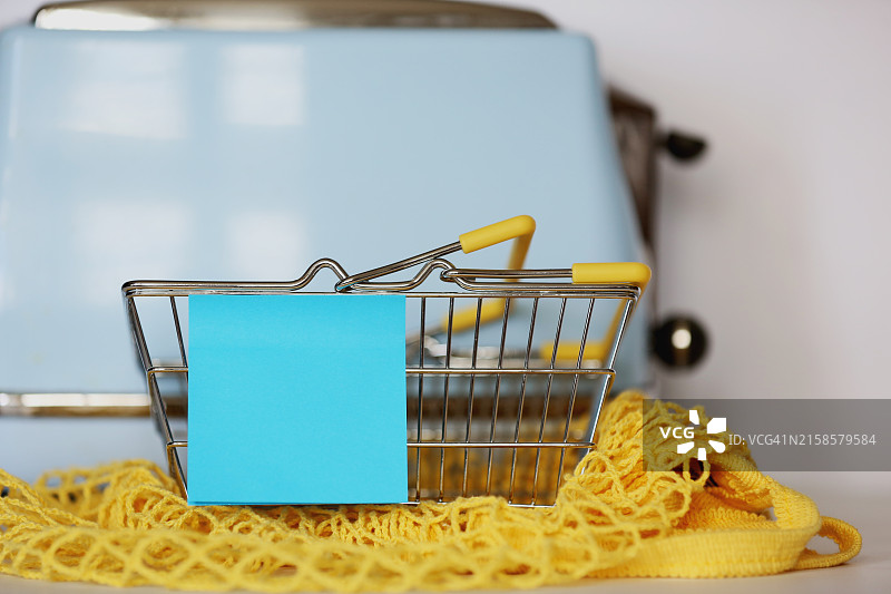 黄色可重复使用棉网袋旁小市场篮子上的蓝色不干胶标签图片素材