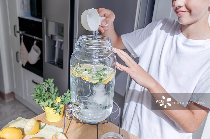 微笑的男孩将糖倒入玻璃罐中图片素材